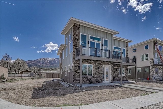 view of front facade featuring a mountain view, a balcony, and a patio