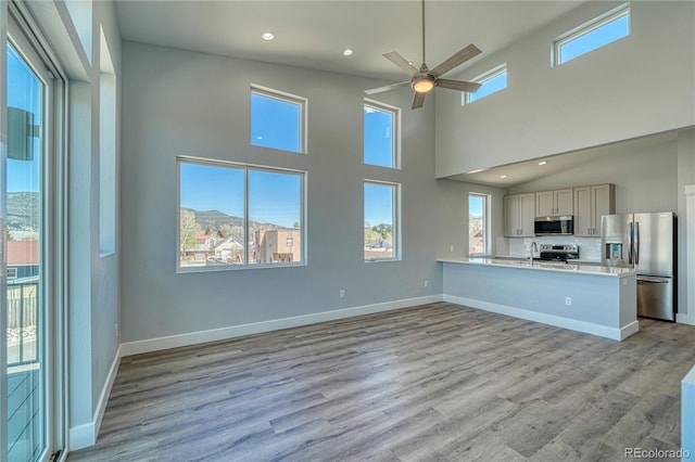 interior space with a mountain view, ceiling fan, a wealth of natural light, appliances with stainless steel finishes, and kitchen peninsula