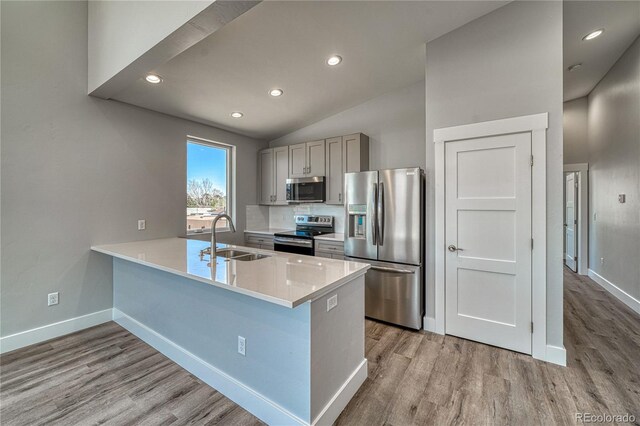 kitchen featuring gray cabinetry, sink, stainless steel appliances, kitchen peninsula, and vaulted ceiling