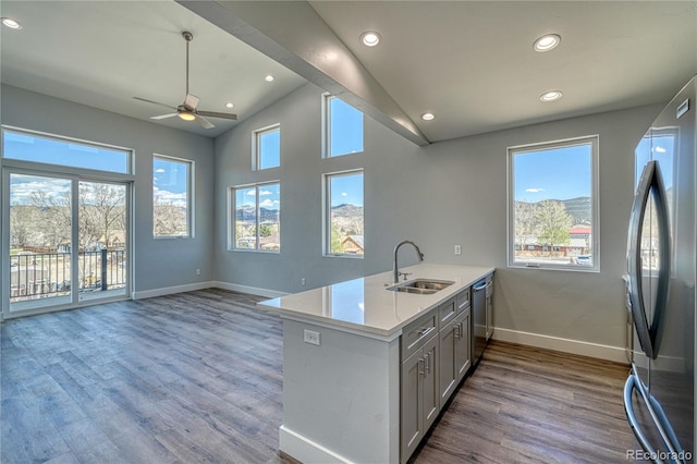 kitchen with kitchen peninsula, appliances with stainless steel finishes, ceiling fan, sink, and light hardwood / wood-style floors