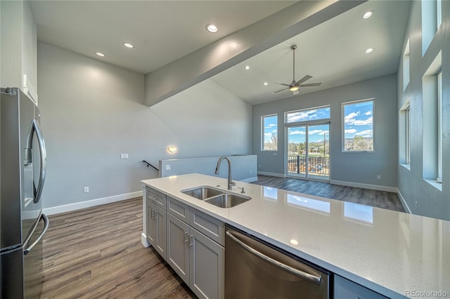 kitchen with sink, ceiling fan, dark hardwood / wood-style floors, light stone countertops, and appliances with stainless steel finishes