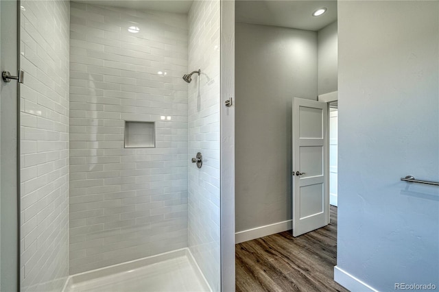 bathroom featuring a tile shower and wood-type flooring