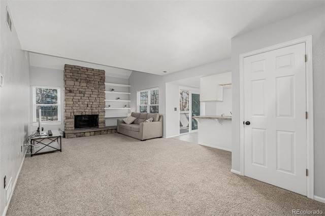 unfurnished living room featuring a stone fireplace, carpet, visible vents, and built in features