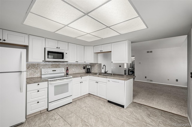 kitchen with white appliances, visible vents, white cabinets, dark countertops, and a sink