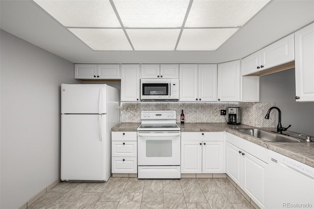 kitchen with white appliances, white cabinetry, a sink, and backsplash