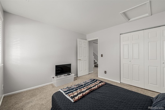 carpeted bedroom with a closet, attic access, and baseboards