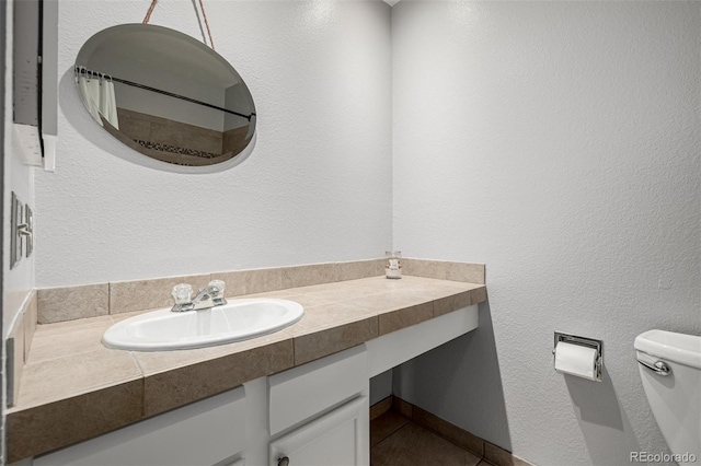 bathroom with toilet, a textured wall, a shower with shower curtain, and vanity