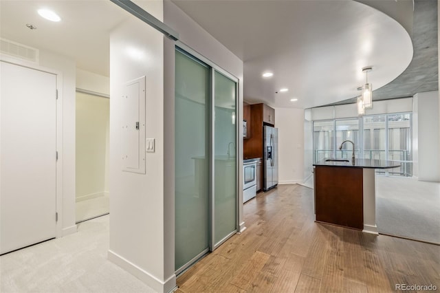kitchen featuring stainless steel refrigerator with ice dispenser, dark countertops, recessed lighting, range, and a sink