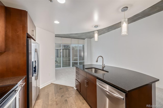 kitchen with a sink, stainless steel appliances, light wood-type flooring, hanging light fixtures, and recessed lighting