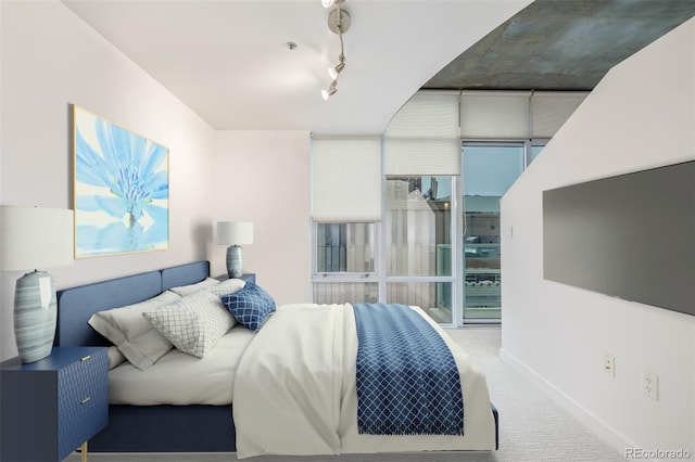 carpeted bedroom with baseboards and track lighting