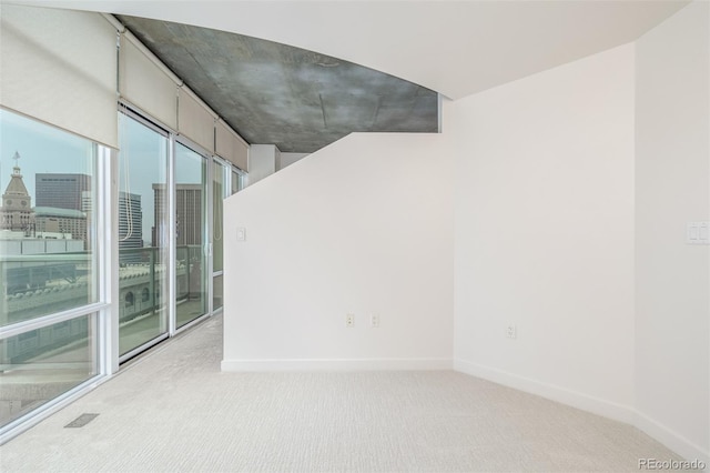 empty room featuring light carpet and baseboards