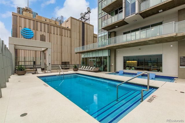community pool featuring a patio, a hot tub, and fence