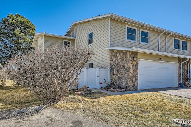 view of home's exterior featuring fence, concrete driveway, a garage, stone siding, and a gate