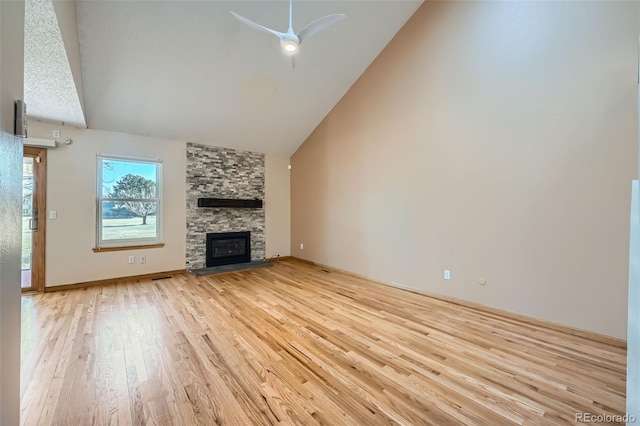 unfurnished living room featuring baseboards, a stone fireplace, light wood-style floors, high vaulted ceiling, and a ceiling fan