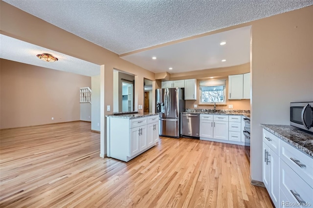 2446 S Vaughn Way Unit A, Aurora, CO 80014 - kitchen with light wood-style flooring, a textured ceiling, white cabinets, and stainless steel appliances