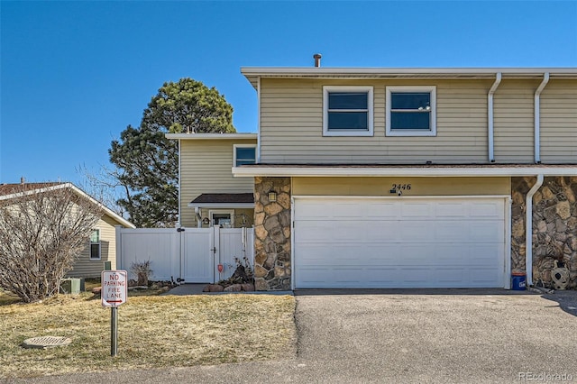2446 S Vaughn Way Unit A, Aurora, CO 80014 - traditional home with fence, stone siding, aphalt driveway, a garage, and a gate