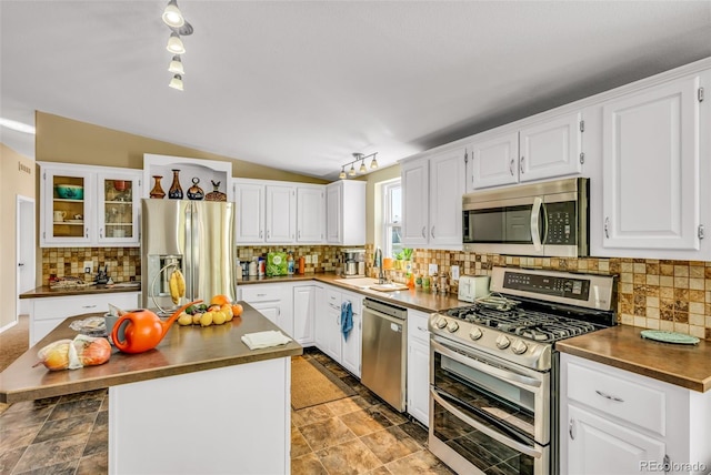 kitchen with lofted ceiling, sink, stainless steel appliances, a center island, and white cabinets