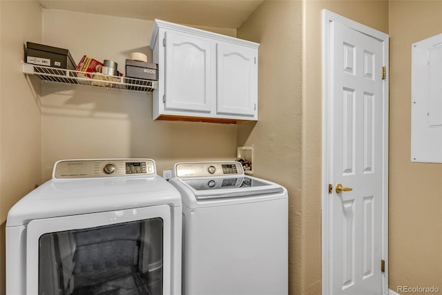 clothes washing area featuring separate washer and dryer, electric panel, and cabinets