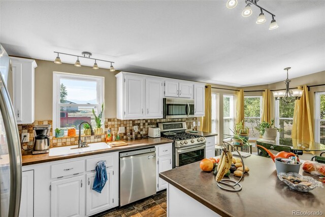 kitchen featuring sink, appliances with stainless steel finishes, plenty of natural light, white cabinets, and decorative backsplash