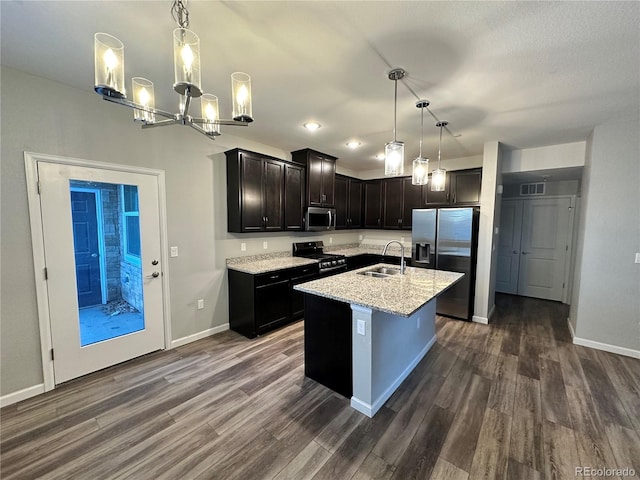 kitchen with appliances with stainless steel finishes, decorative light fixtures, a kitchen island with sink, and sink