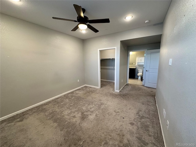 unfurnished bedroom with a spacious closet, light carpet, ceiling fan, and a closet