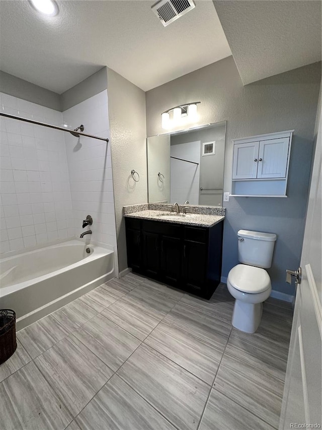 full bathroom with vanity, toilet, tiled shower / bath combo, and a textured ceiling