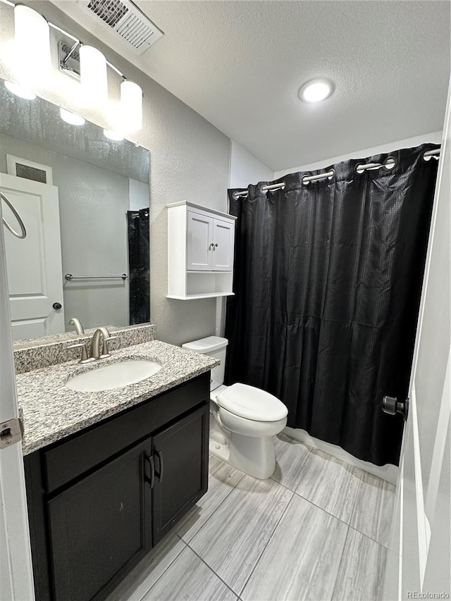 bathroom with a shower with curtain, vanity, toilet, and a textured ceiling