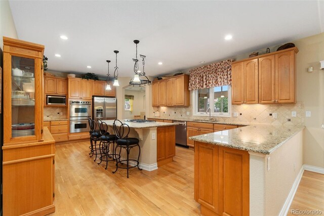 3806 S Dawson St, Aurora, CO 80014 - kitchen with appliances with stainless steel finishes, a kitchen breakfast bar, a sink, light wood-type flooring, and backsplash