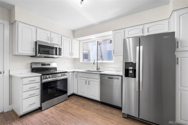 1519 S Sable Blvd Unit C, Aurora, CO 80012 - kitchen with stainless steel appliances, a sink, white cabinets, and light wood-style flooring