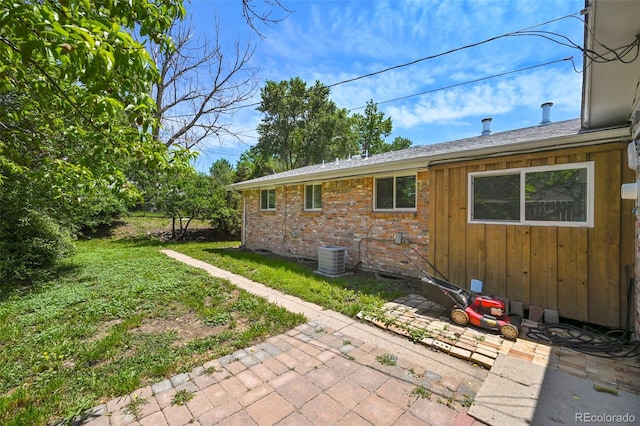 6432 Zephyr St, Arvada, CO 80004 - view of property exterior with a patio, a lawn, brick siding, central AC, and board and batten siding