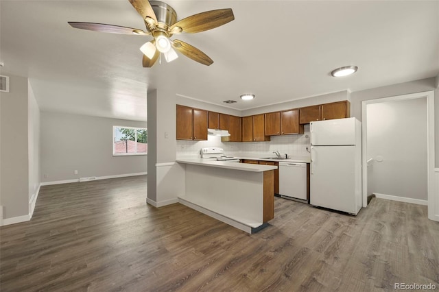 6432 Zephyr St, Arvada, CO 80004 - kitchen featuring white appliances, light countertops, under cabinet range hood, brown cabinetry, and a peninsula
