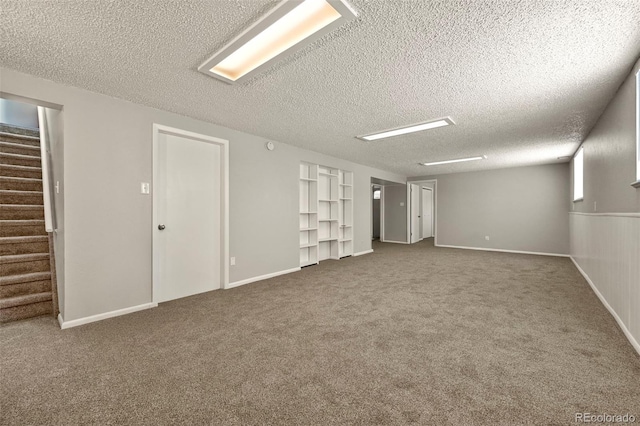 6432 Zephyr St, Arvada, CO 80004 - finished basement with stairs, a textured ceiling, dark colored carpet, built in shelves, and baseboards