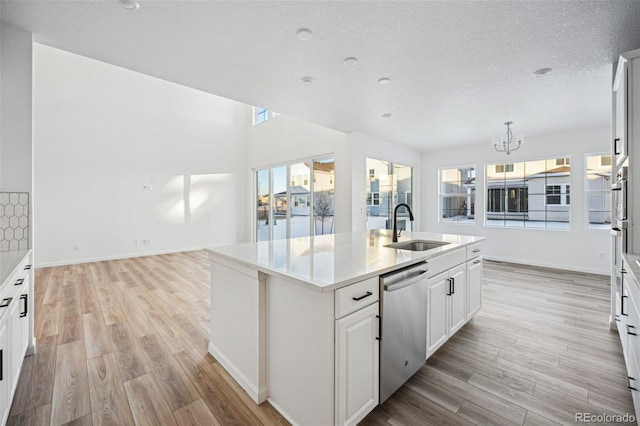 kitchen featuring sink, white cabinets, dishwasher, and a center island with sink