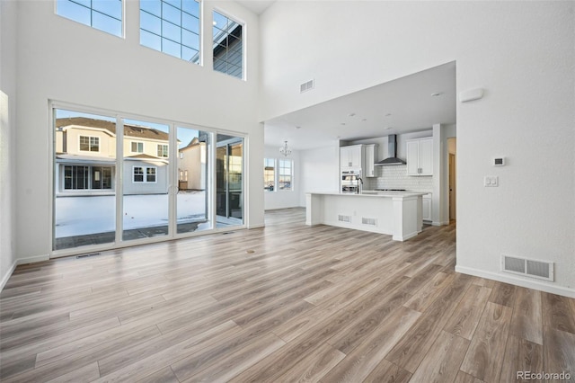 unfurnished living room featuring light hardwood / wood-style floors and a high ceiling