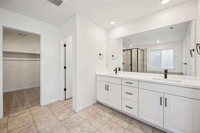 bathroom with a shower with door, vanity, and tile patterned floors