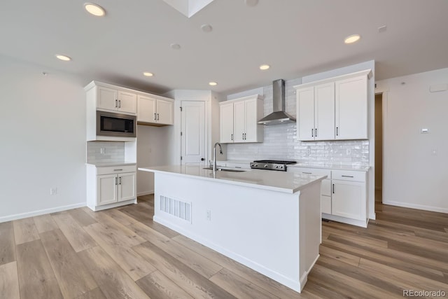 kitchen featuring stainless steel appliances, white cabinetry, and wall chimney exhaust hood