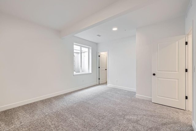 carpeted empty room with beamed ceiling