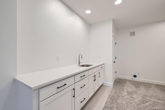 laundry area featuring sink and light carpet