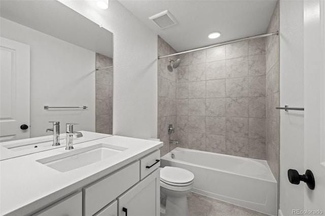 full bathroom with tile patterned flooring, tiled shower / bath, vanity, and toilet