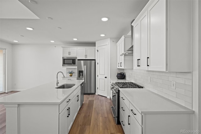 kitchen with hardwood / wood-style floors, sink, white cabinets, stainless steel appliances, and a center island with sink