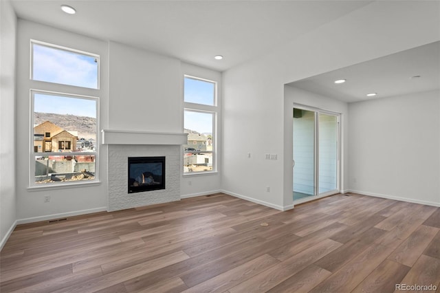 unfurnished living room featuring hardwood / wood-style floors, a fireplace, and a high ceiling