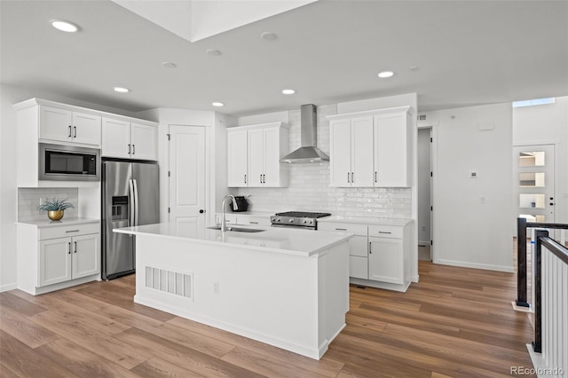 kitchen featuring white cabinetry, wall chimney range hood, and appliances with stainless steel finishes