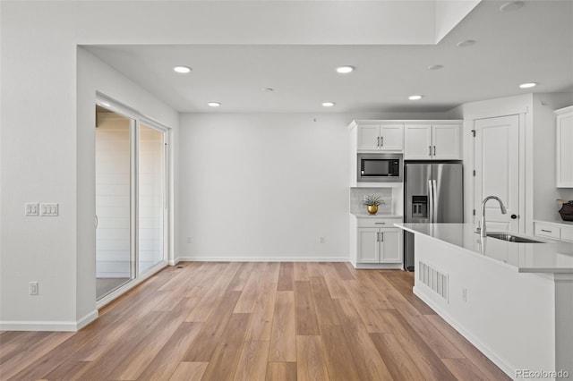 kitchen featuring sink, tasteful backsplash, stainless steel appliances, light hardwood / wood-style floors, and white cabinets