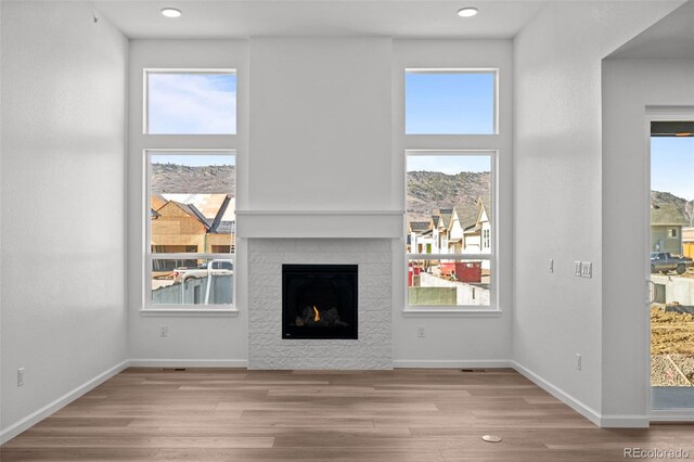 unfurnished living room with plenty of natural light, a mountain view, and light hardwood / wood-style floors