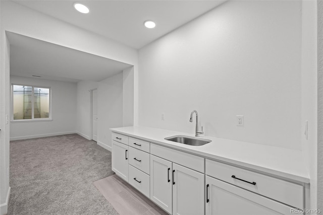 interior space featuring sink, light colored carpet, and white cabinets