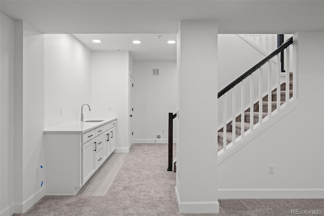 interior space featuring sink, light carpet, and white cabinets