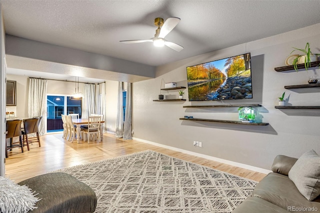 living area with ceiling fan, wood finished floors, and baseboards