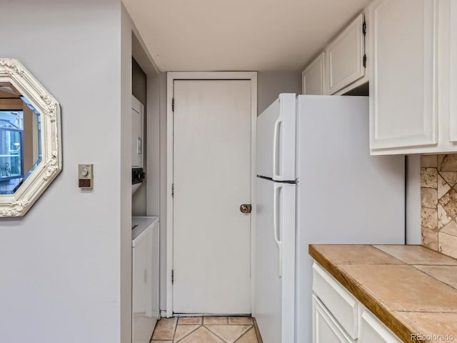 kitchen with light tile patterned flooring, white fridge, and white cabinets