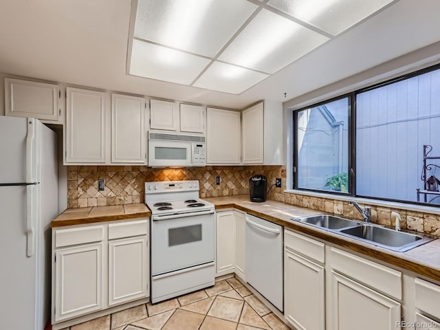 kitchen featuring white cabinetry, tasteful backsplash, white appliances, sink, and light tile patterned floors