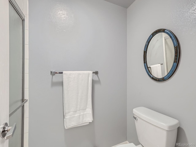 bathroom with a shower with shower door and toilet